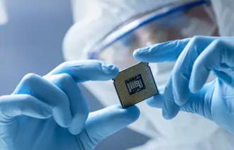 A person in protective gear holding a microchip

Description automatically generated